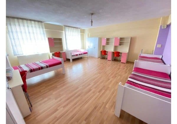 Dört kişilik odada dört tek yatak ve pencere önü çalışma masaları